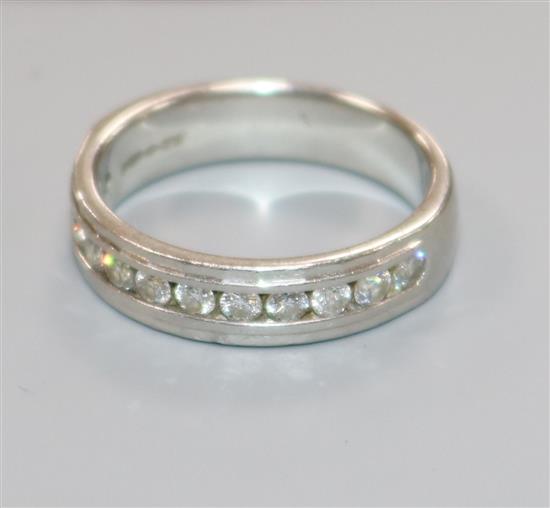 A modern platinum and twelve stone channel set diamond half eternity ring, size M.
